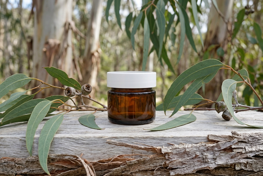 Eucalyptus globulus showcase with the same amber jar and a fresh natural eucalyptus-wood surface